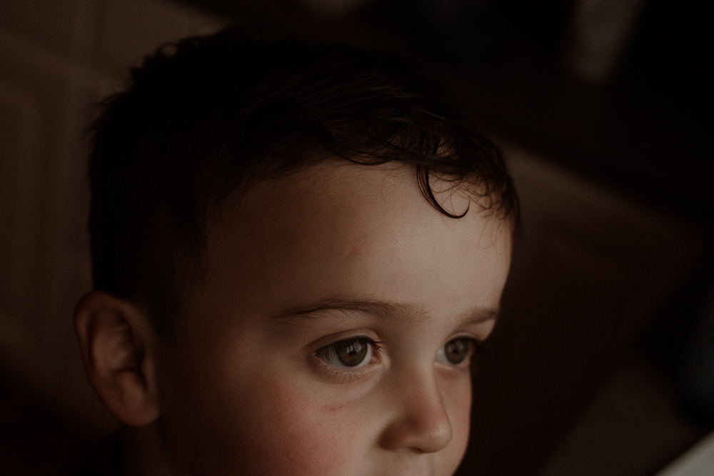 emotive photo of a boy looking outside with a curl from his wet hair