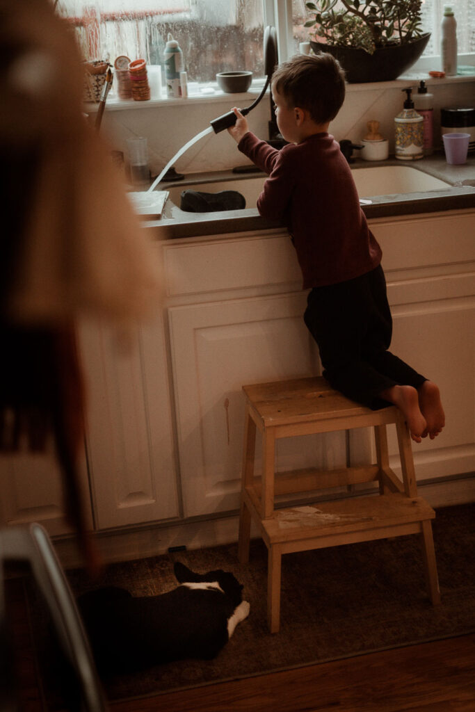 cinematic and emotive photography session of a boy playing in the kitchen sink